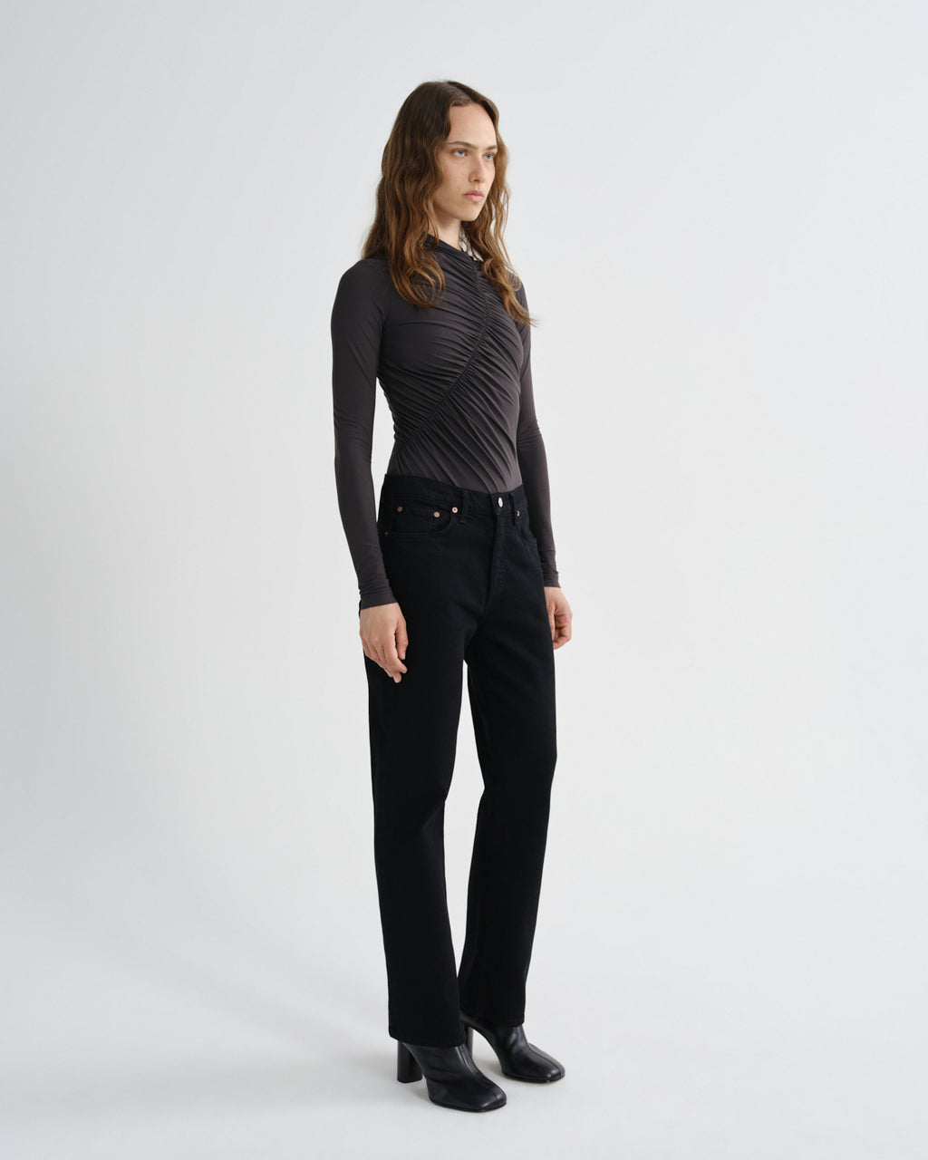 Person wearing black pants and a brown top on a white background
