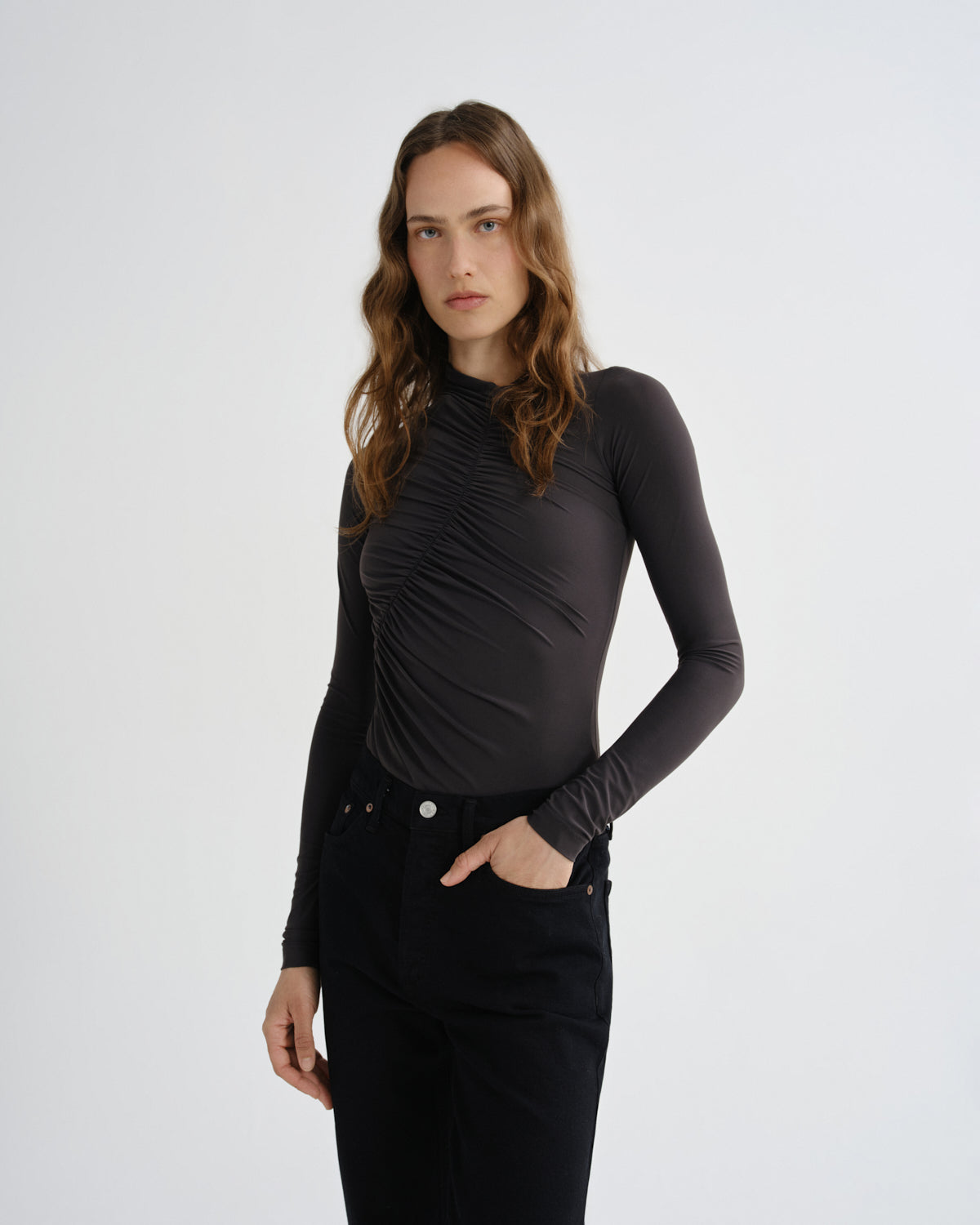 Woman wearing a brown long-sleeve top against a white background