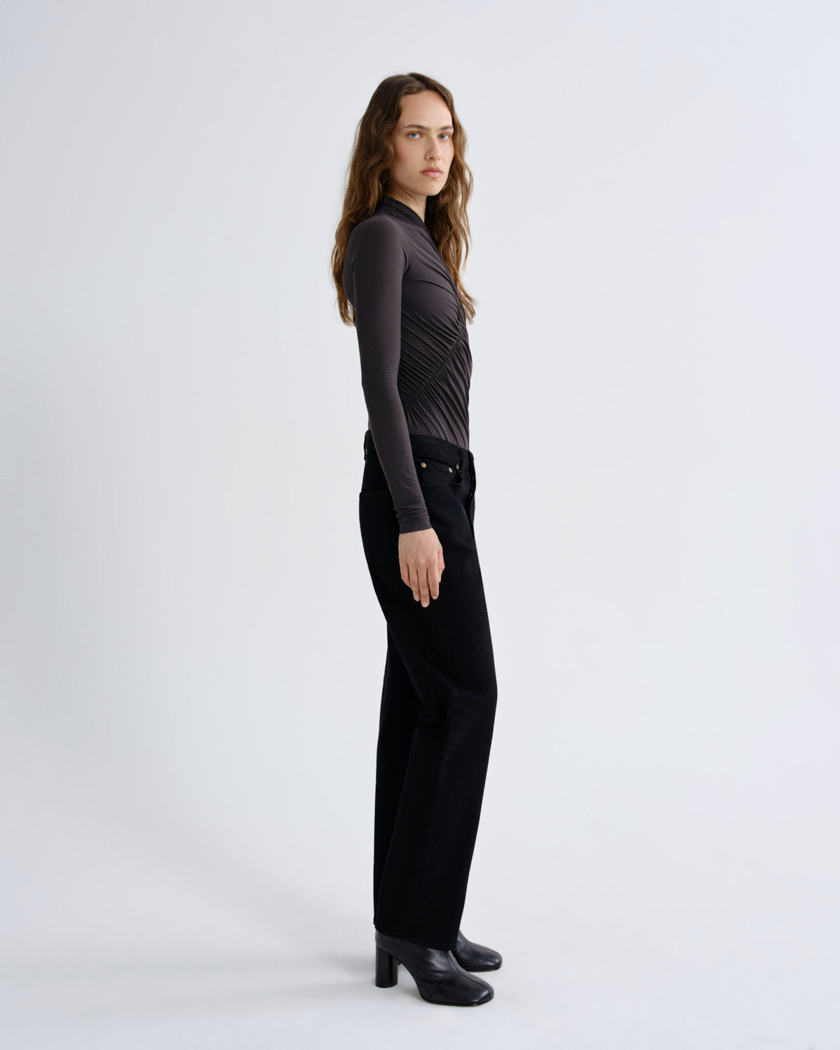 Person wearing black pants and a brown top on a white background