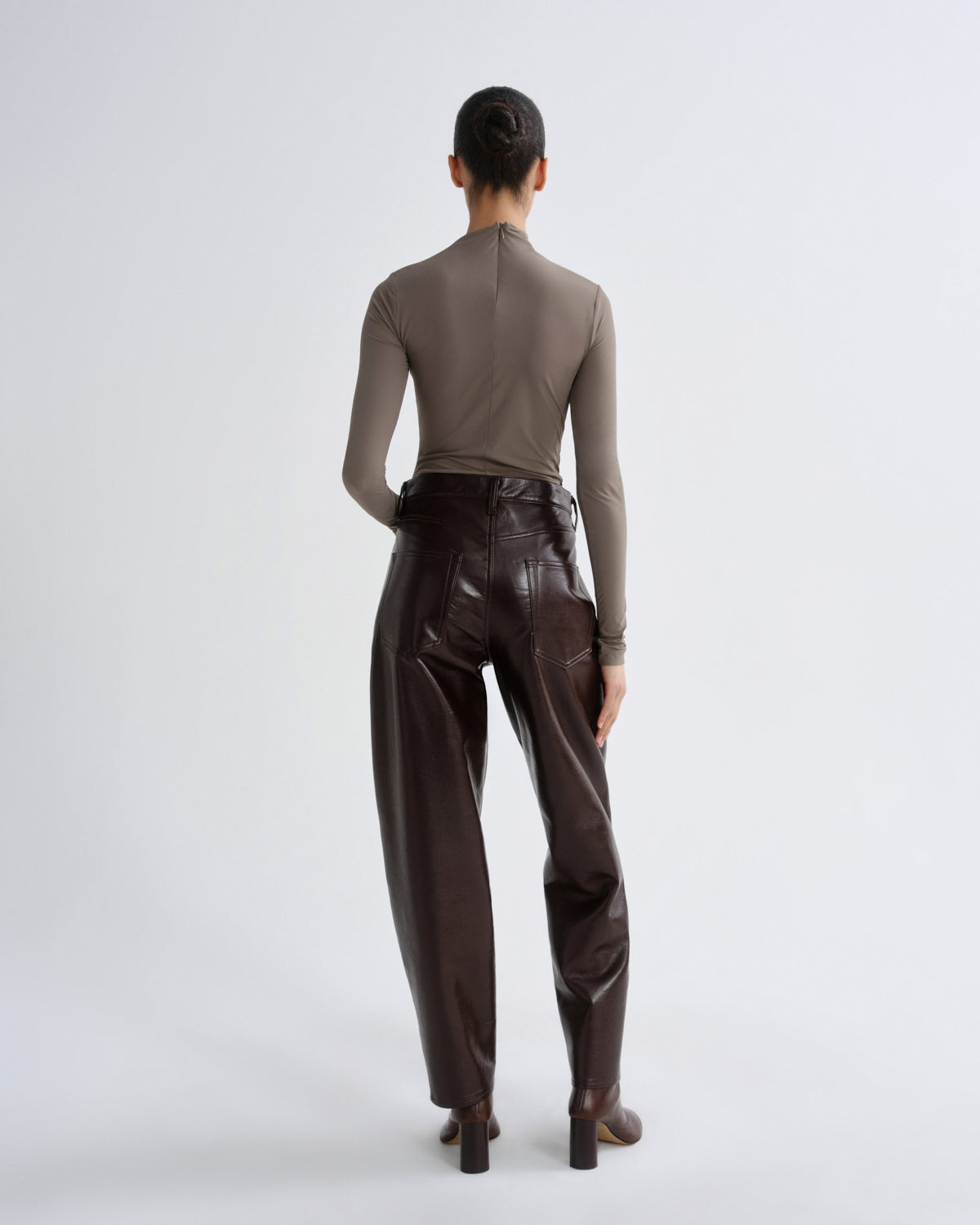 Person wearing a brown leather outfit on a white background