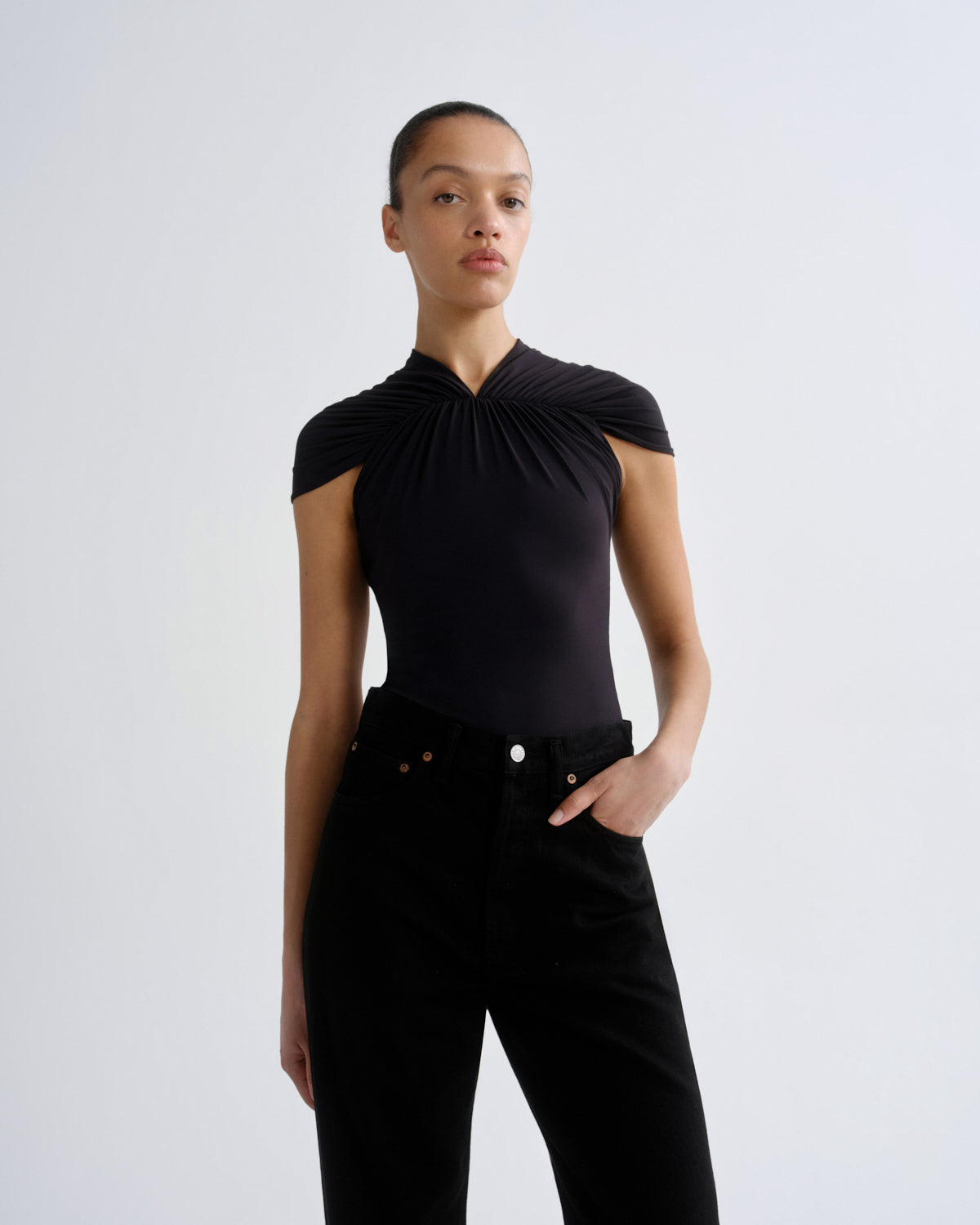 Person wearing a black sleeveless top and black pants on a white background