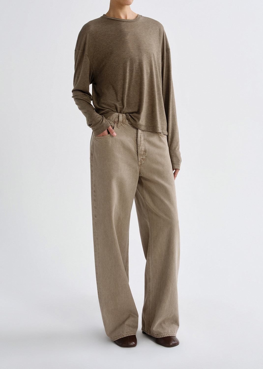 Person wearing a brown long-sleeve top and beige wide-leg pants on a grey background