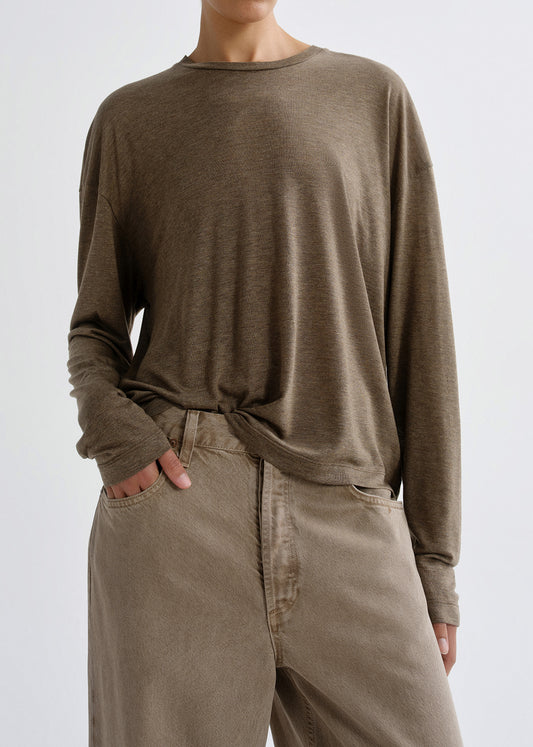 Person wearing a brown long-sleeve shirt and beige pants on a grey background