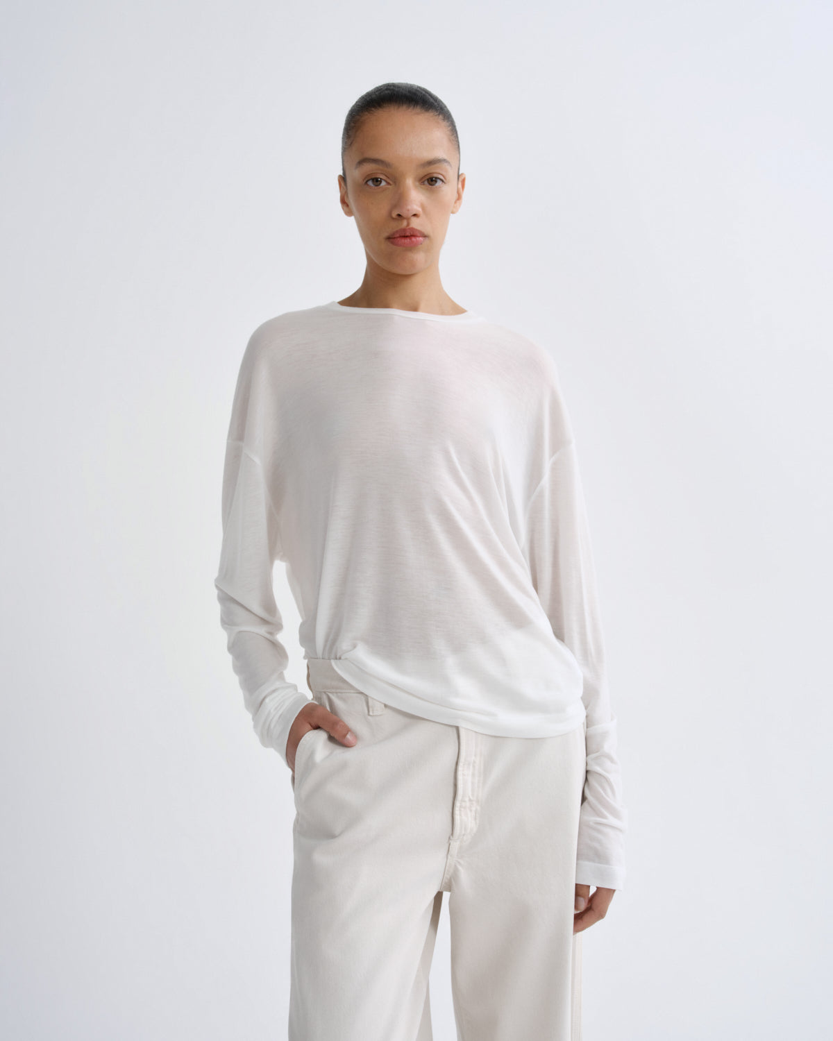 Person wearing a white long-sleeve top and pants on a light gray background
