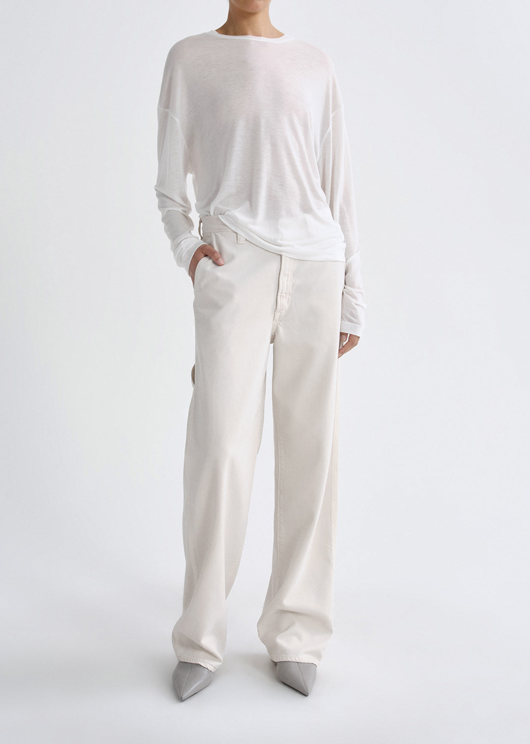 Person wearing a white long-sleeve top and wide-leg pants on a grey background