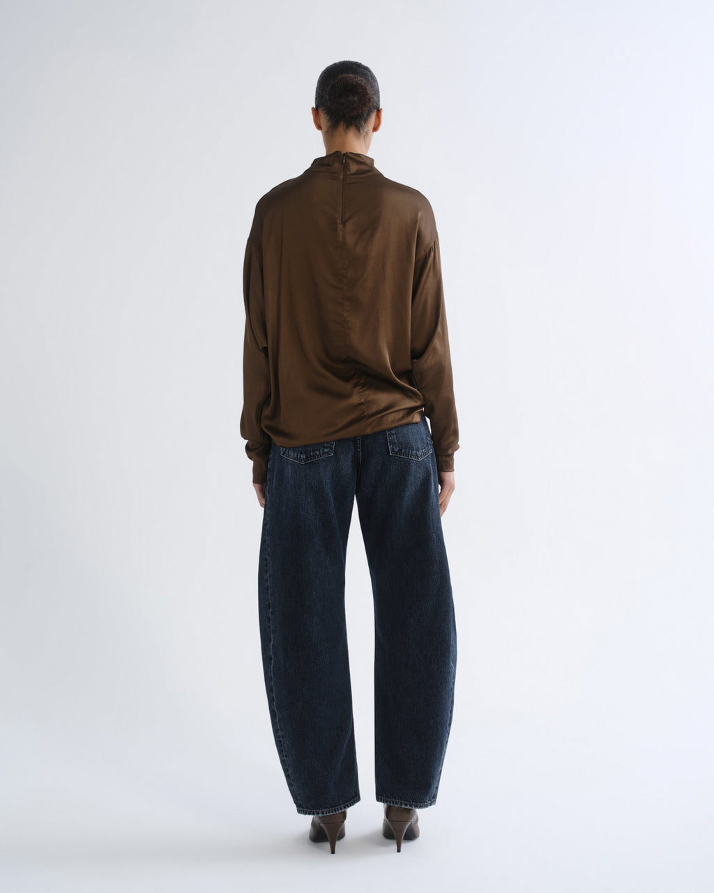 Person wearing brown turtleneck top and dark blue jeans, back view