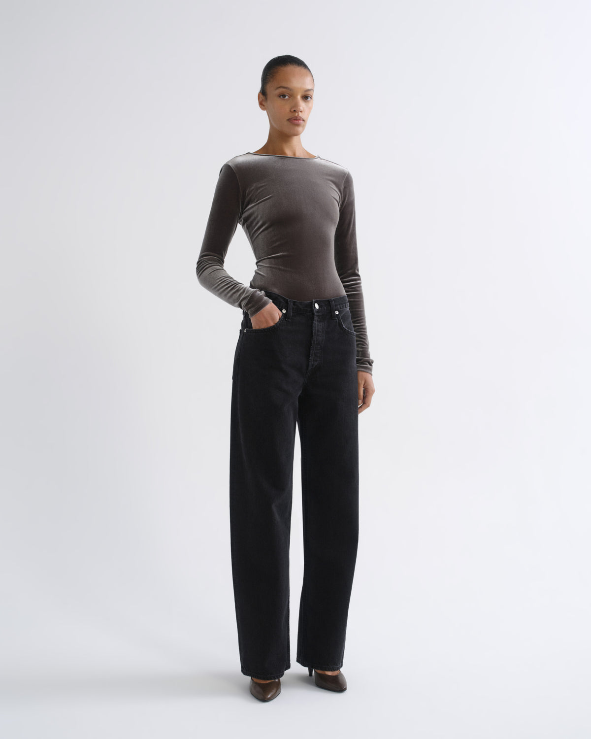 Person wearing brown long sleeve bodysuit and black jeans, front three-quarter view