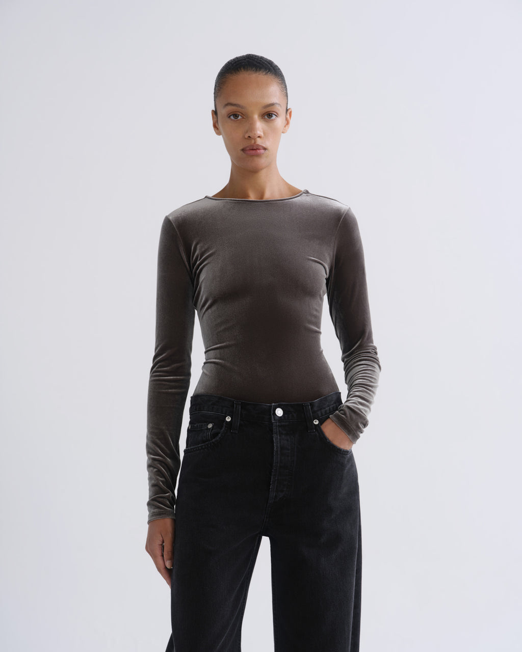Person wearing brown long sleeve bodysuit and black jeans, front view