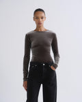 Person wearing brown long sleeve bodysuit and black jeans, front view