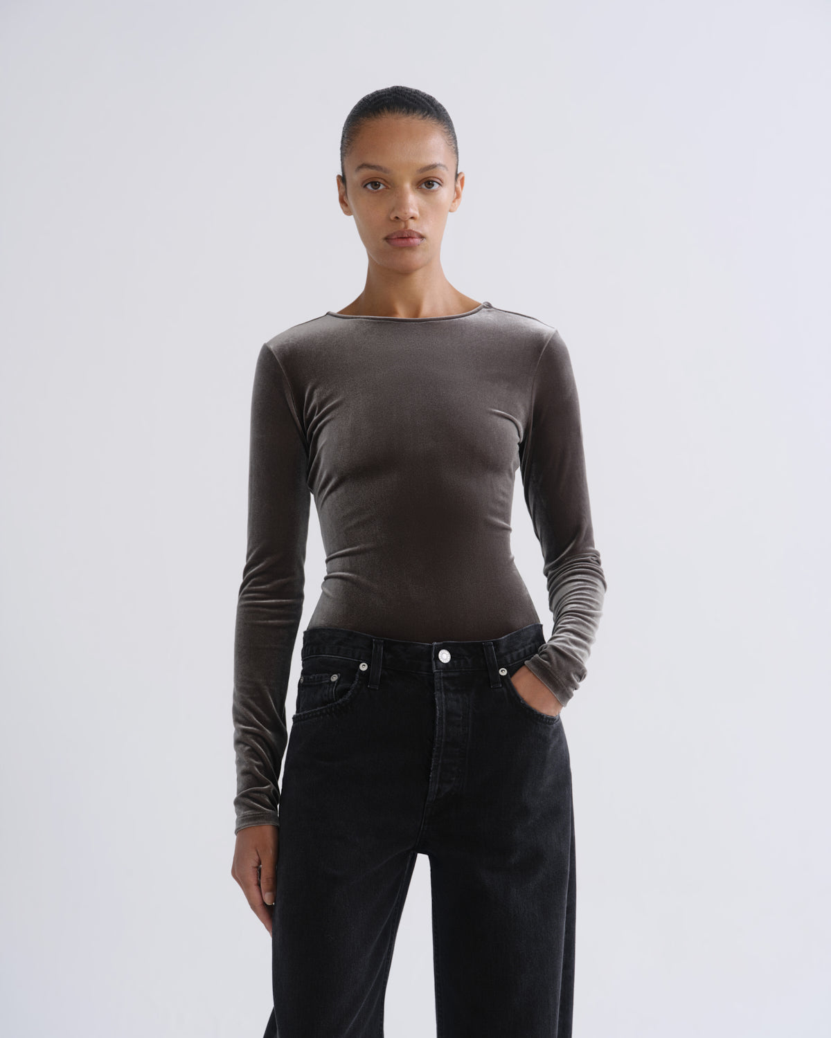 Person wearing brown long sleeve bodysuit and black jeans, front view