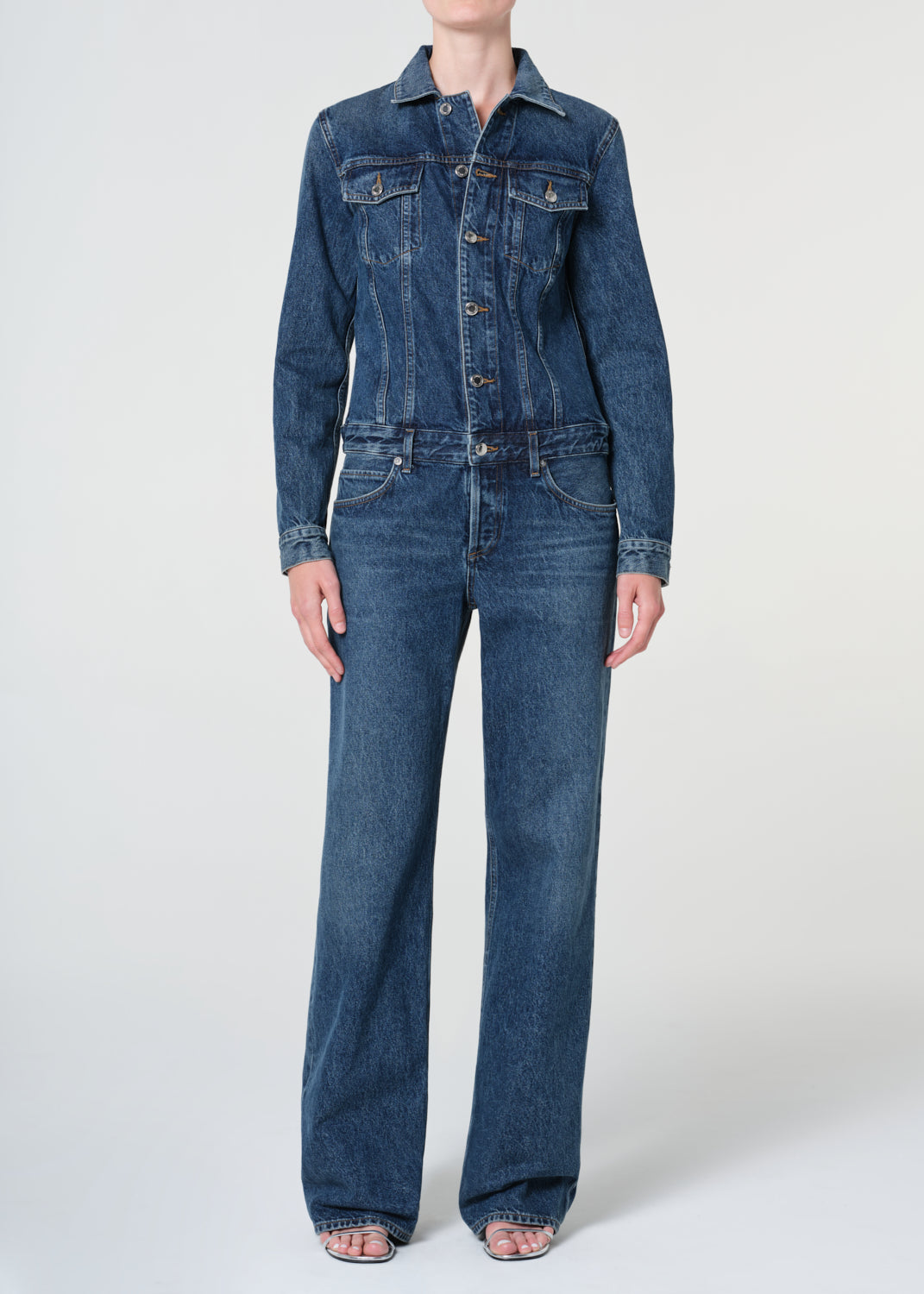 Person wearing a blue denim jumpsuit on a white background