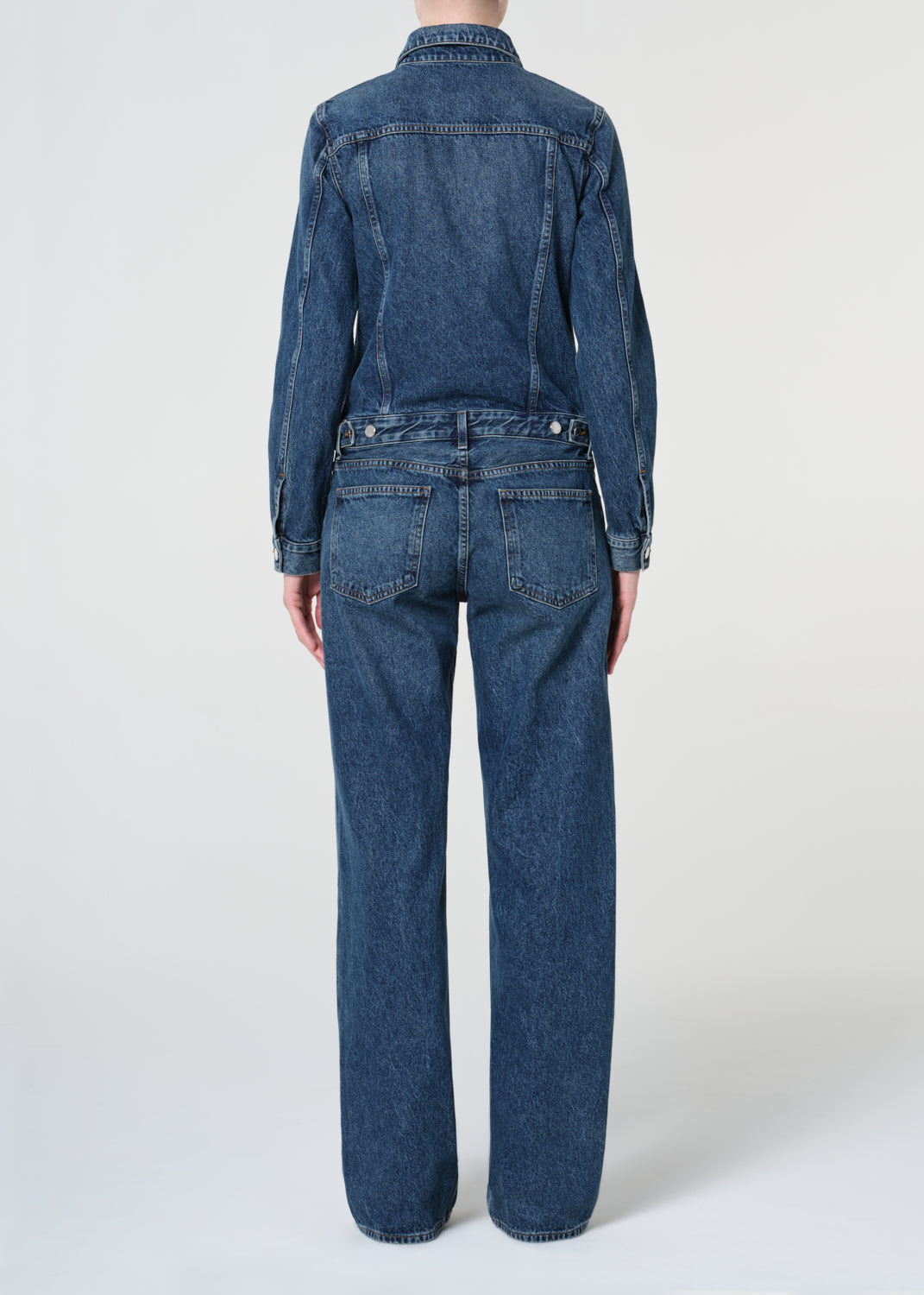 Person wearing a blue denim jumpsuit on a white background