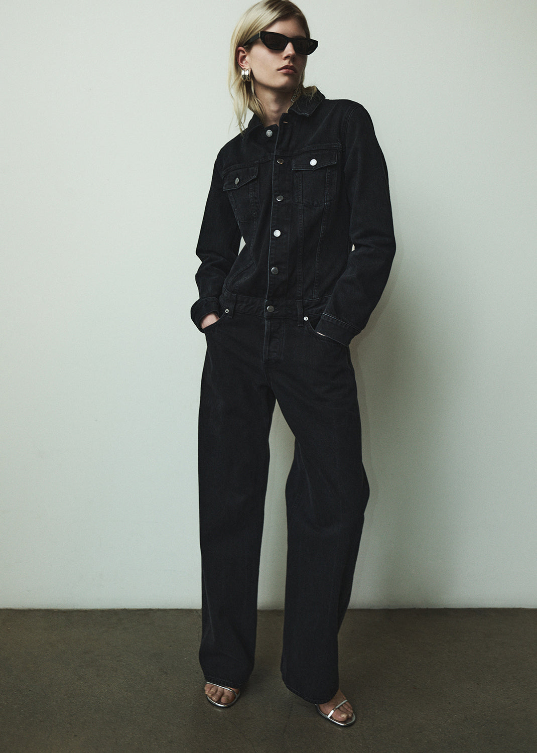 Person wearing a black jumpsuit against a plain background