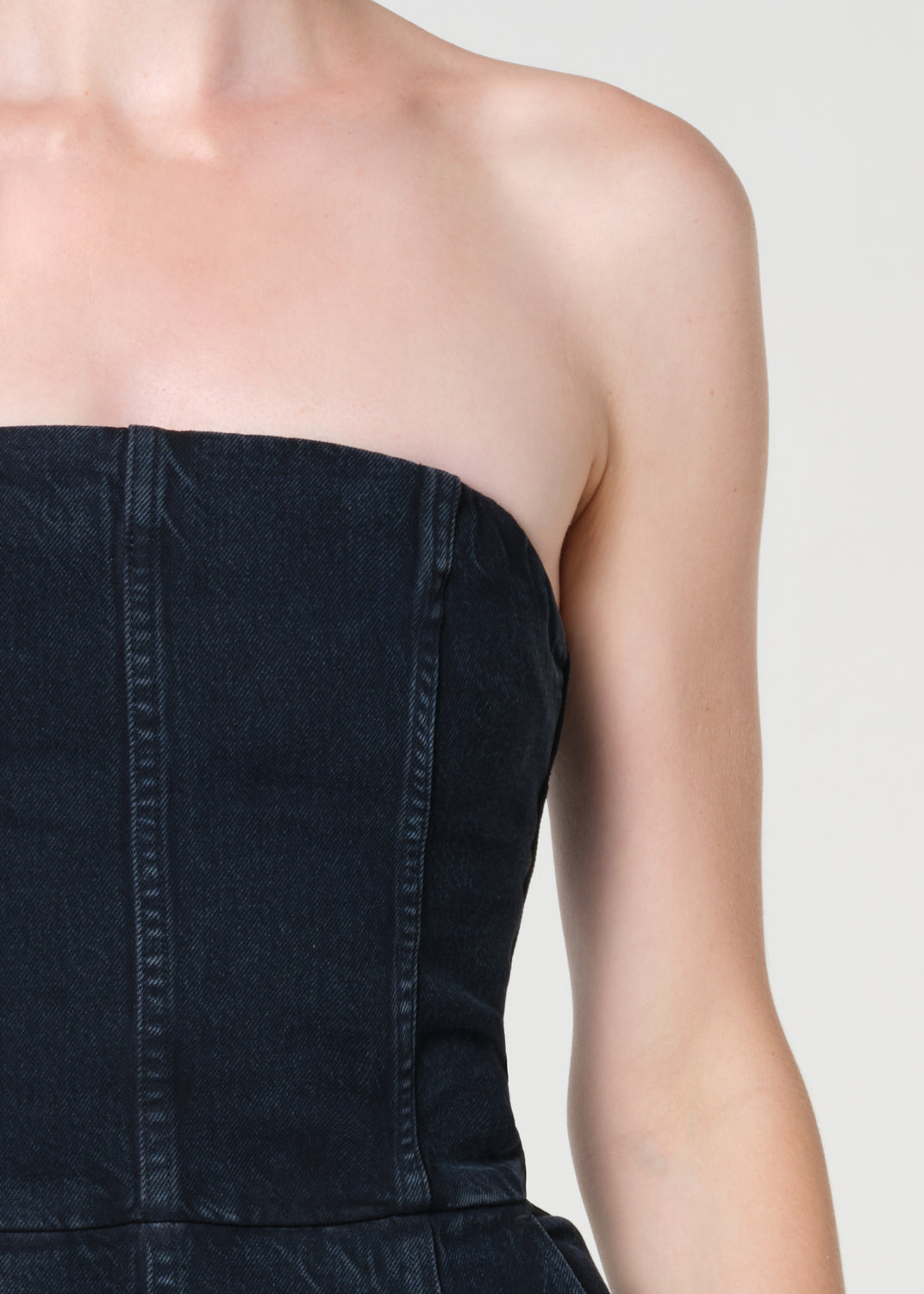 Black strapless dress worn by a person on a plain background