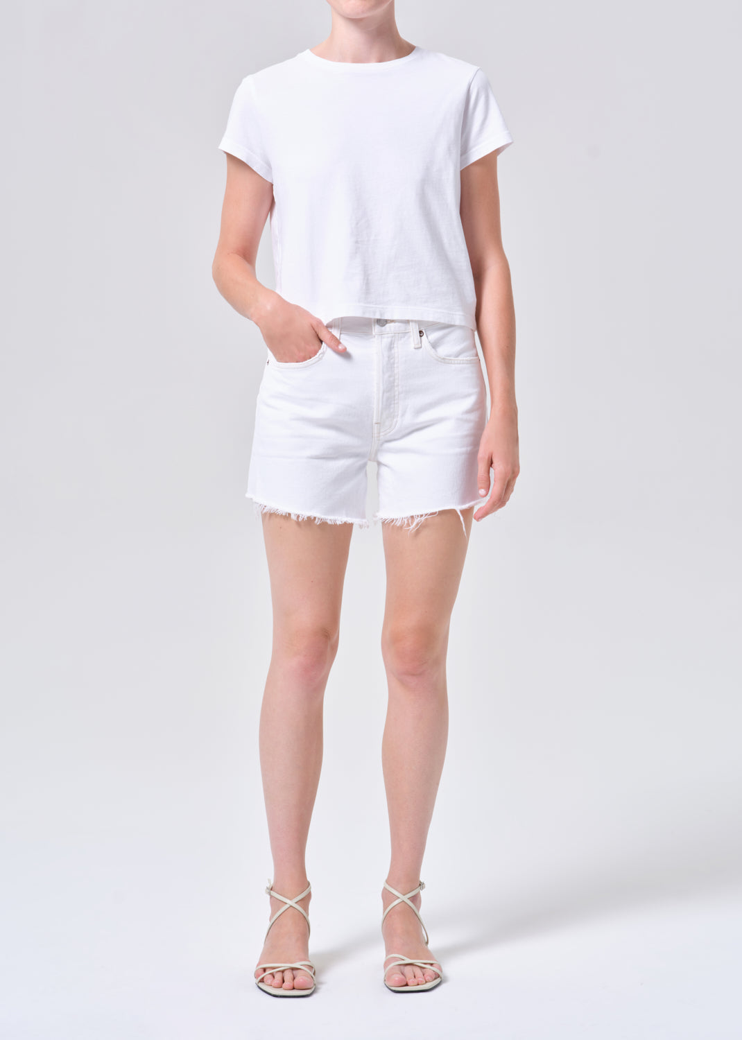 Person wearing a white t-shirt and white shorts on a light gray background