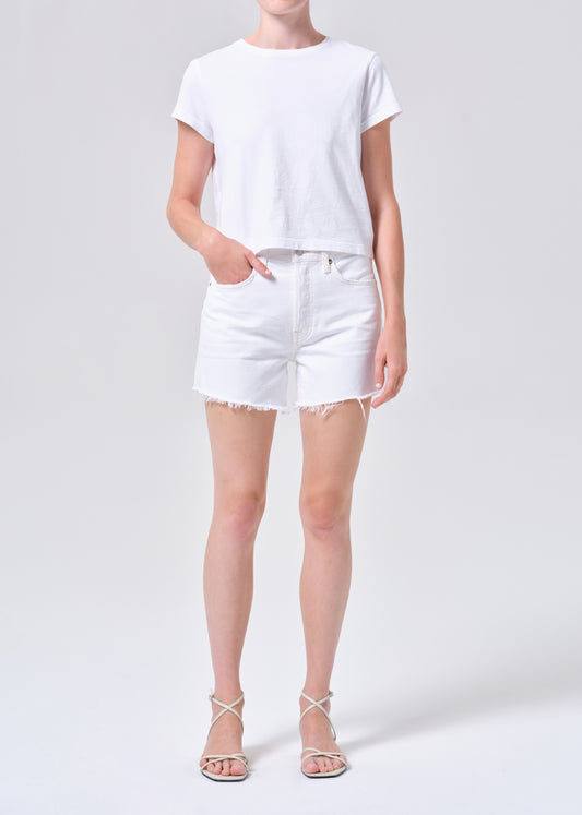 Person wearing a white t-shirt and white shorts on a light gray background