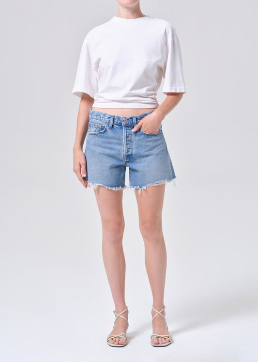Person wearing a white t-shirt and light blue denim shorts on a white background