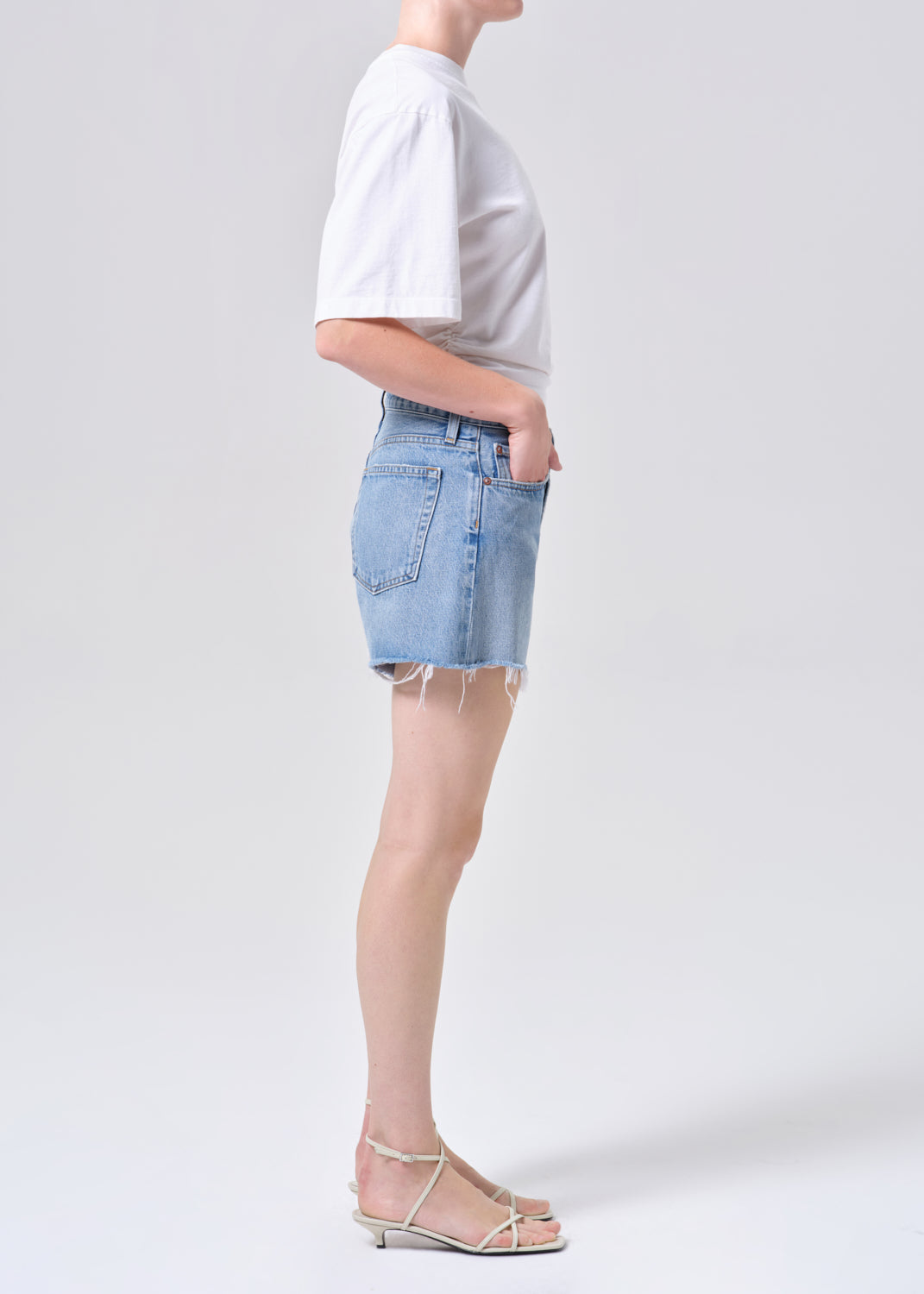 Person wearing a white t-shirt and light blue denim shorts on a plain background