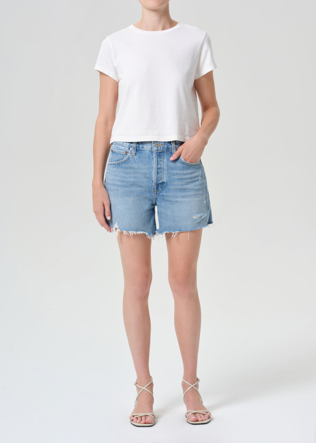 Person wearing a white t-shirt and denim shorts on a plain background