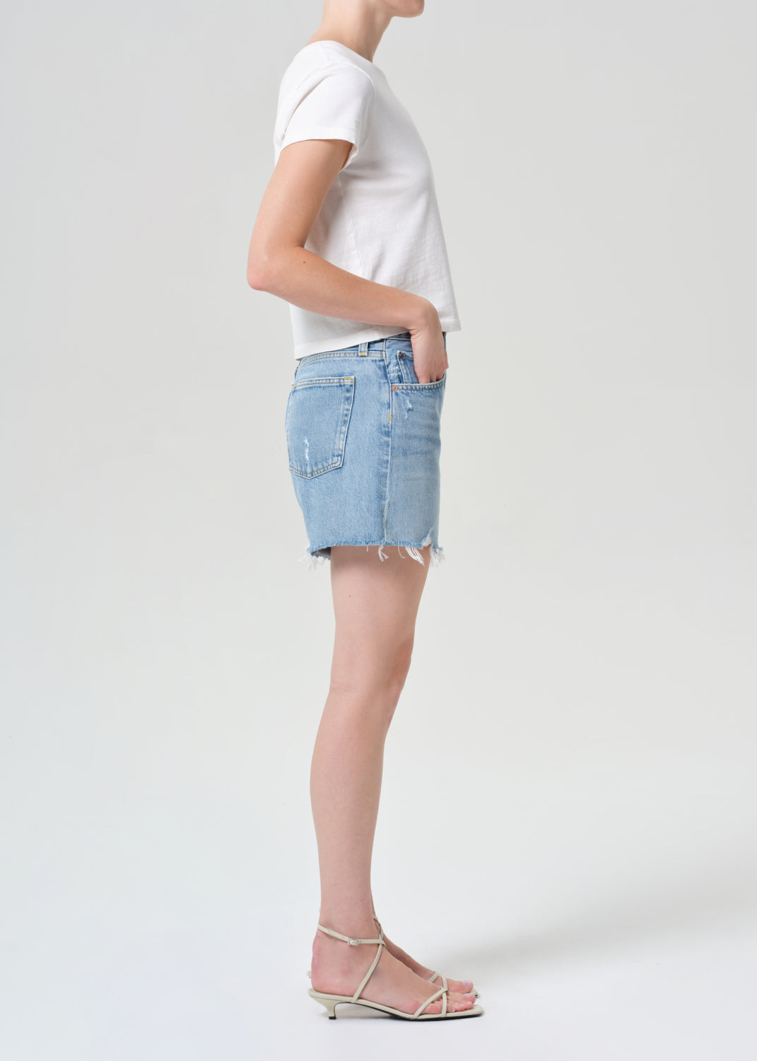 Person wearing a white t-shirt and light blue denim skirt on a plain background
