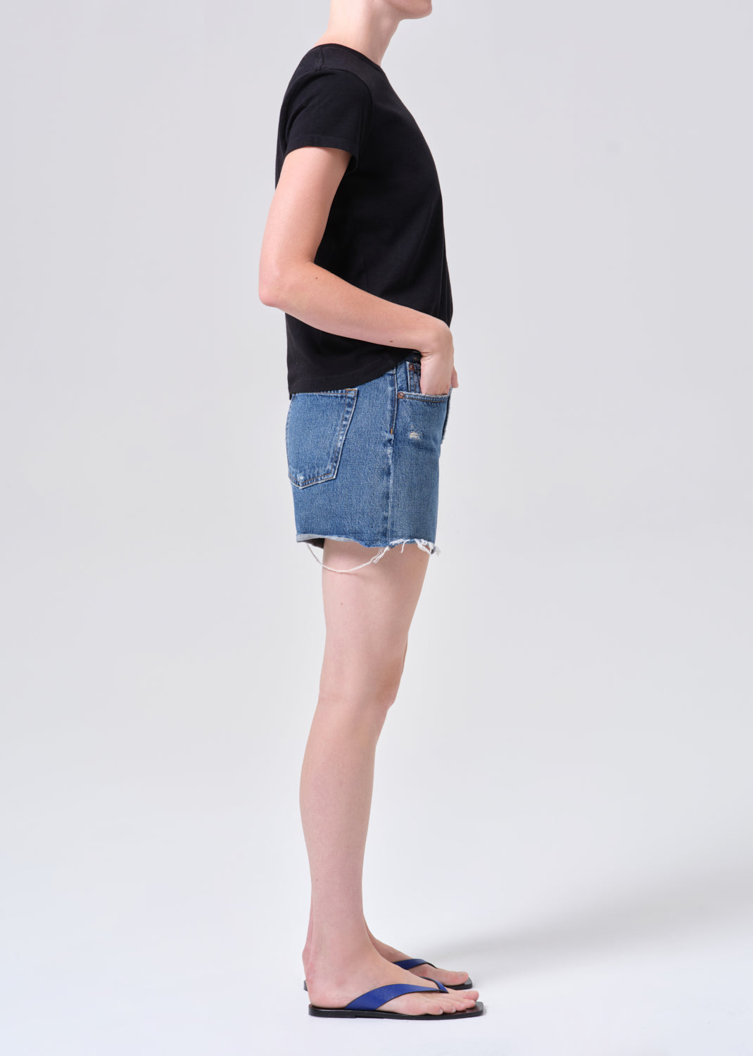 Person wearing a black t-shirt and blue denim skirt on a white background