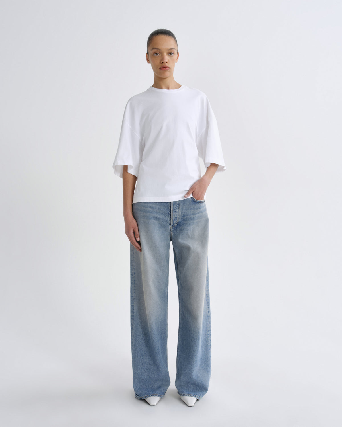 Person wearing a white t-shirt and light blue jeans on a white background