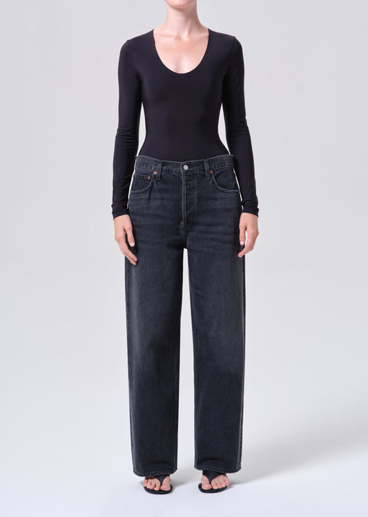 Person wearing black long-sleeve top and dark jeans on a white background