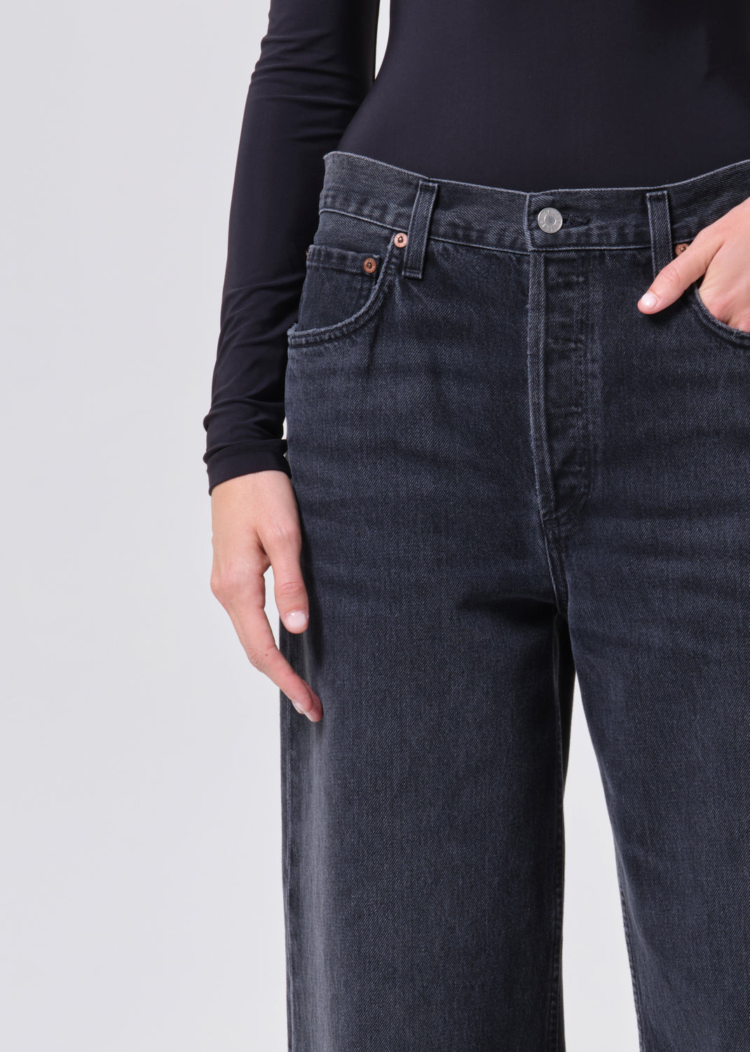 Person wearing dark blue jeans on a light gray background