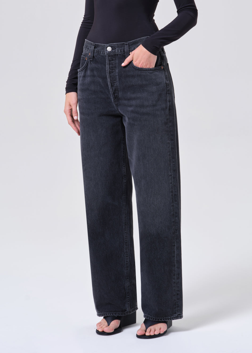 Person wearing black high-waisted jeans on a white background