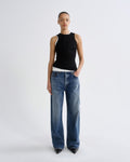 Person wearing a black sleeveless top and blue jeans on a white background