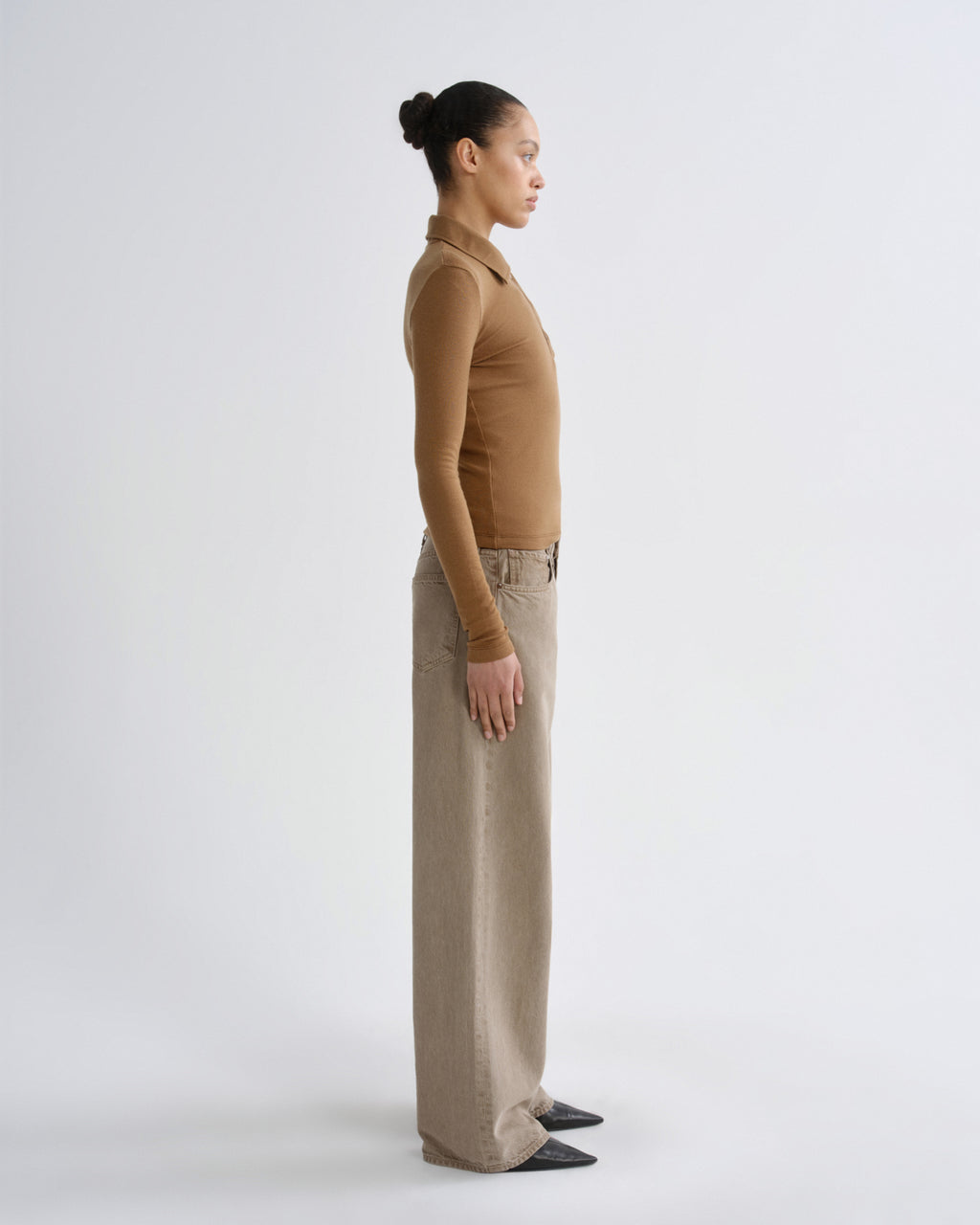 Person wearing a brown top and beige pants on a white background