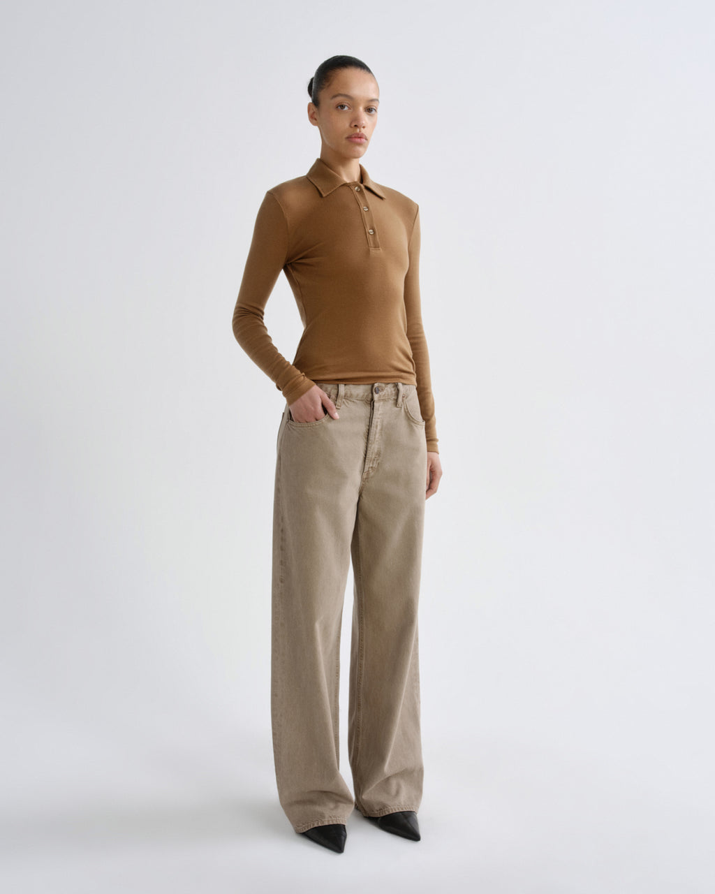 Woman wearing a brown sleeveless top and beige pants on a white background