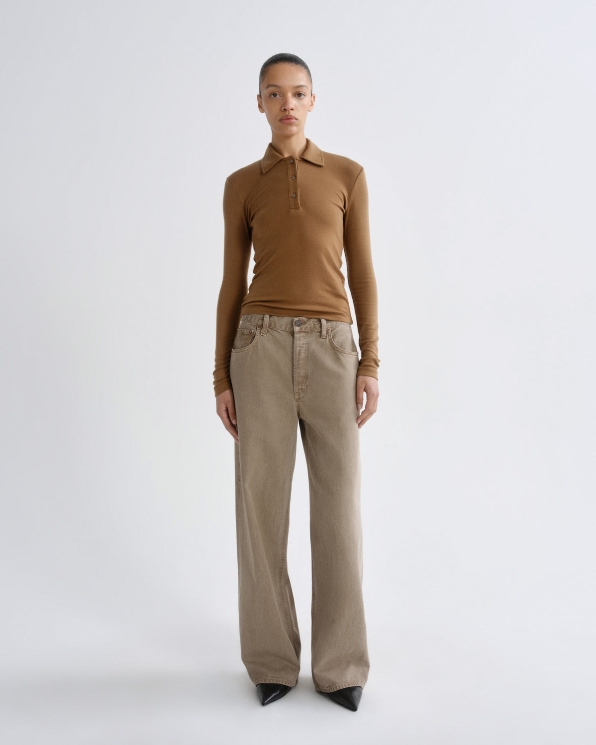 Person wearing a brown long-sleeve shirt and beige pants on a white background