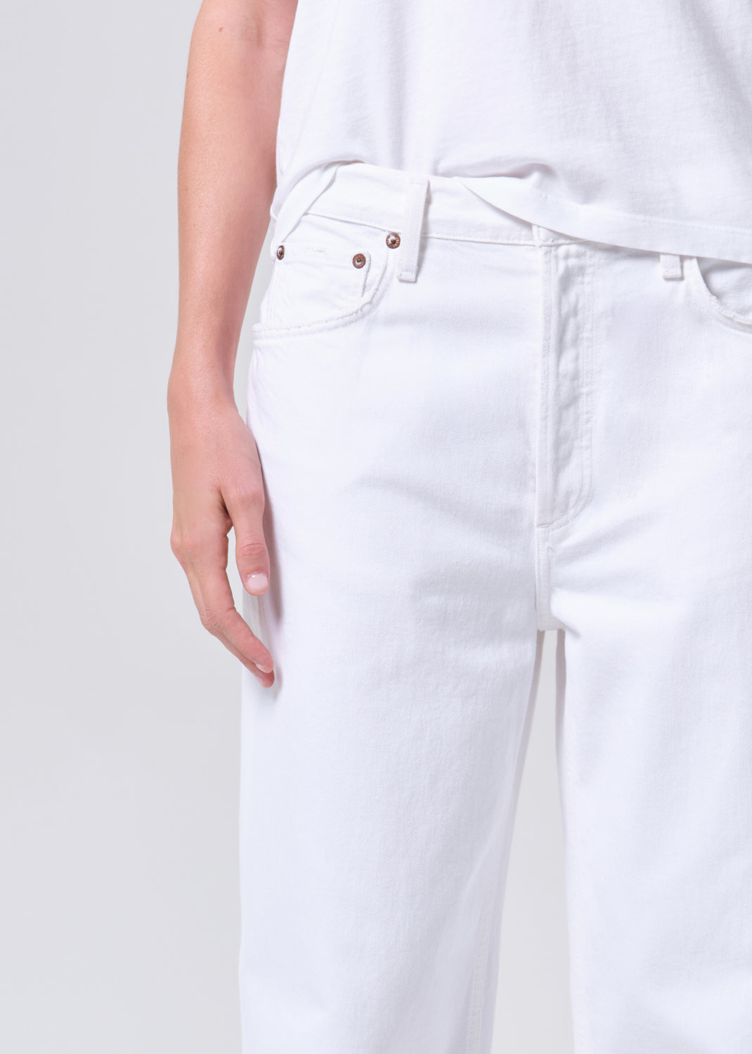 White jeans worn by a person on a light gray background