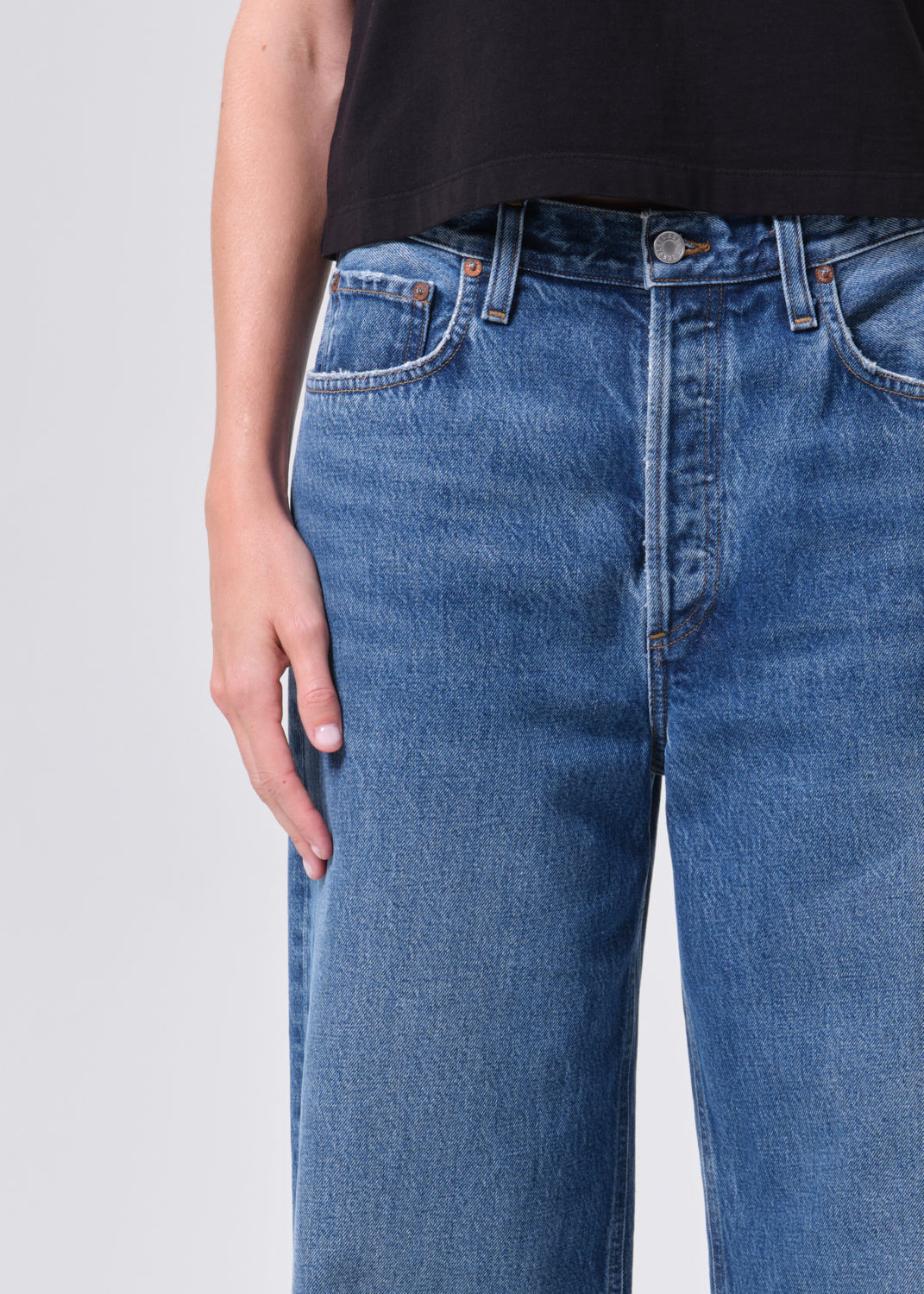 Person wearing blue jeans with a plain background