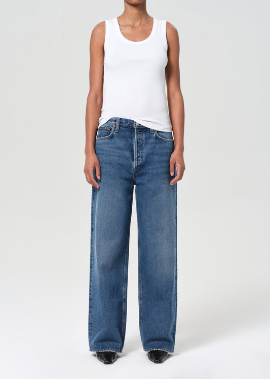 Person wearing a white tank top and blue jeans on a white background