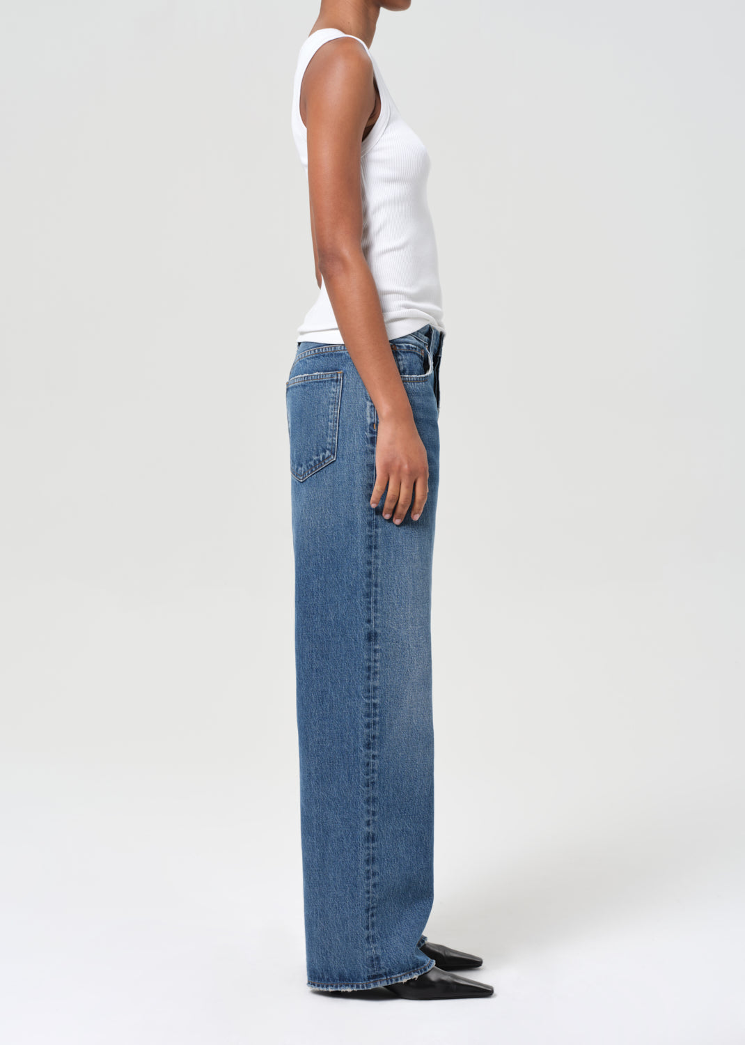 Person wearing blue jeans and a white tank top on a white background