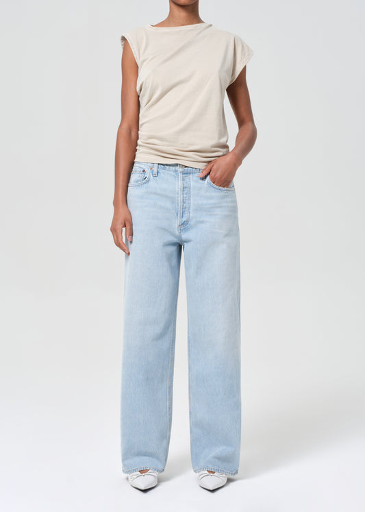 Person wearing a beige top and light blue jeans on a white background