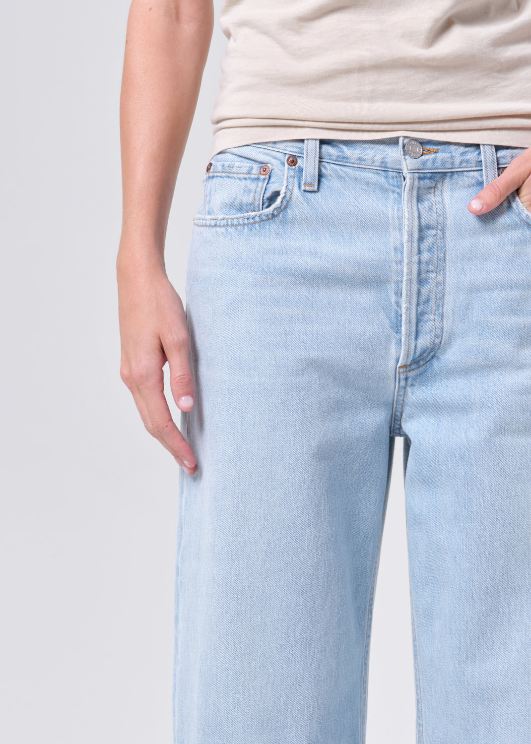 Light blue jeans worn by a person on a plain background