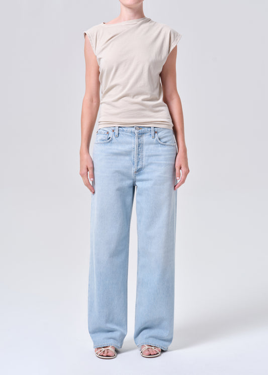 Person wearing a beige top and light blue jeans on a white background