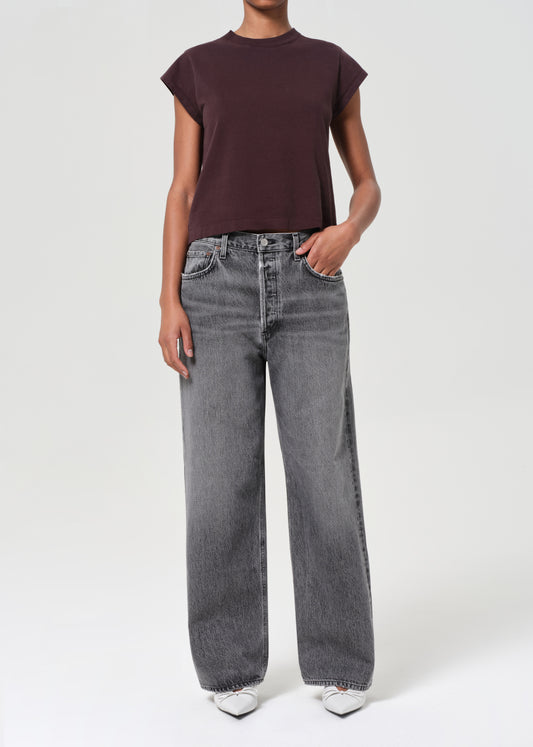 Person wearing a brown t-shirt and gray jeans on a white background