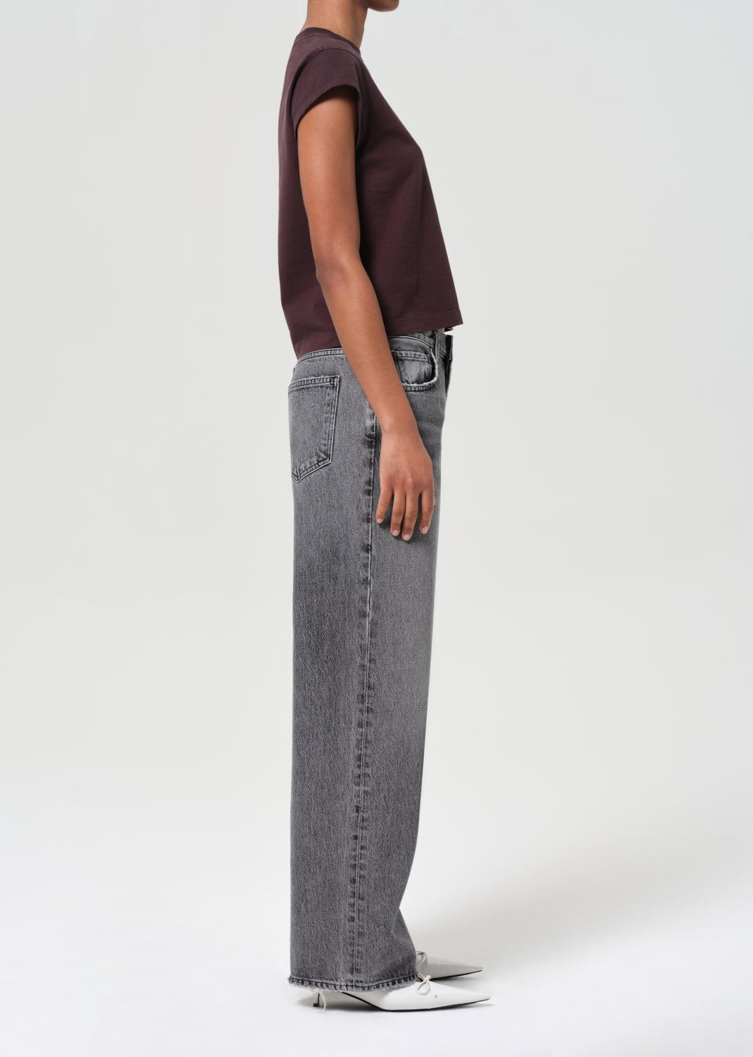 Person wearing a maroon t-shirt and gray jeans on a white background