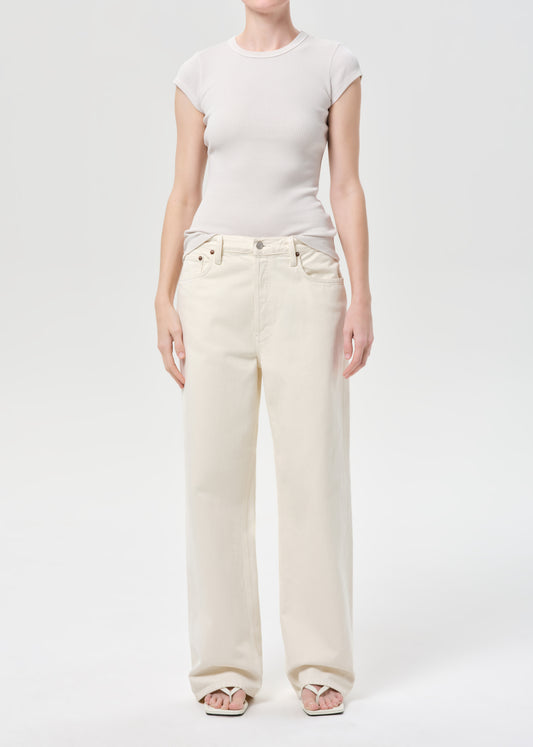 Person wearing a white t-shirt and cream-colored wide-leg jeans on a light gray background