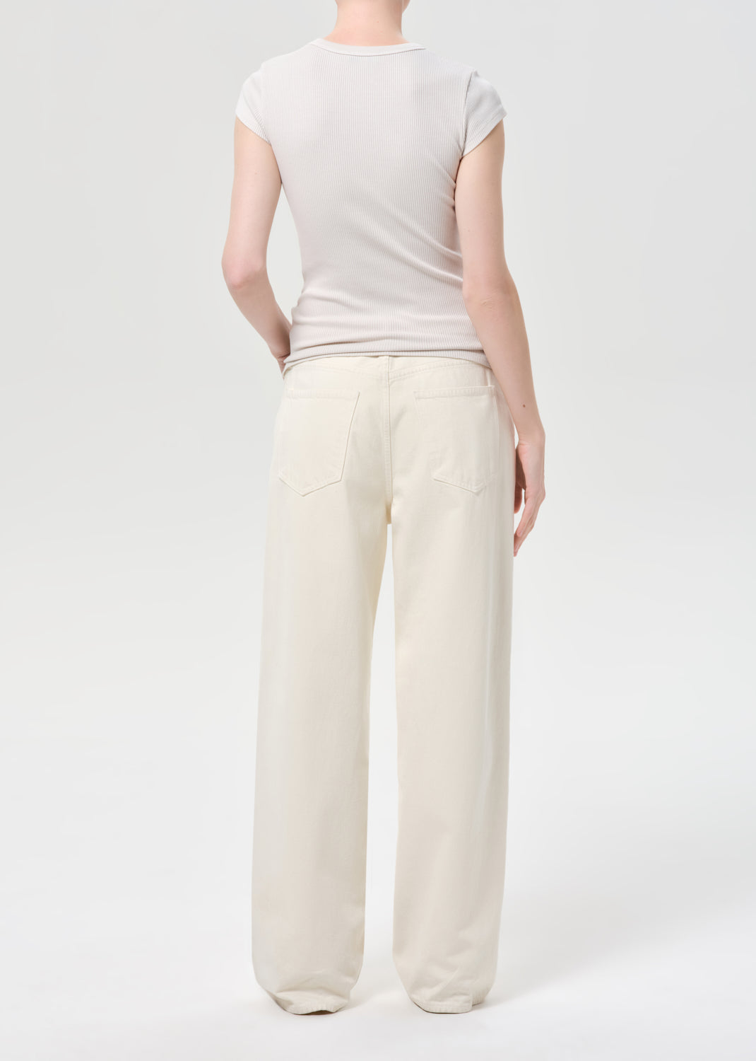 Person wearing a plain white t-shirt and light-colored pants on a white background
