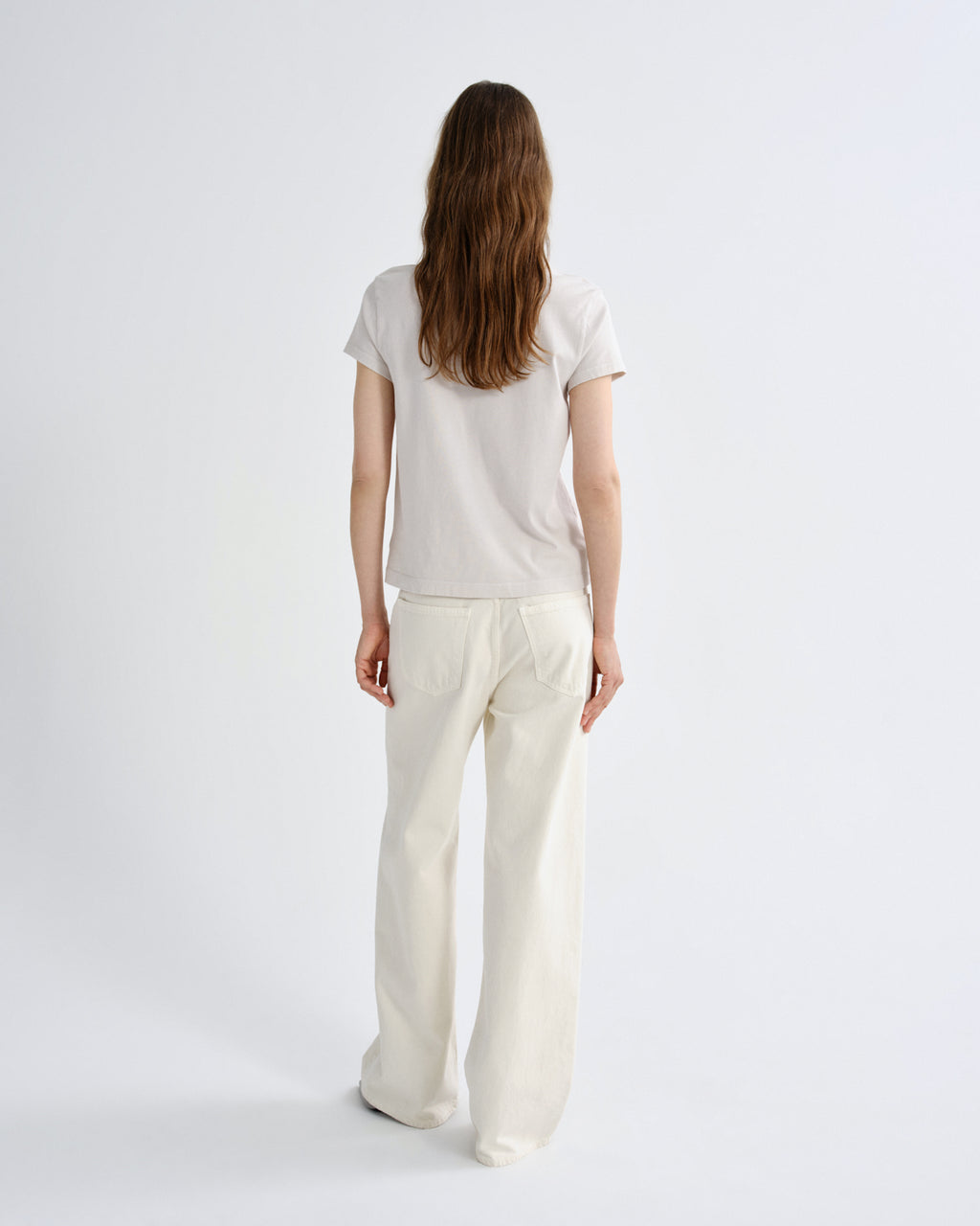 Person wearing a white t-shirt and pants on a light gray background