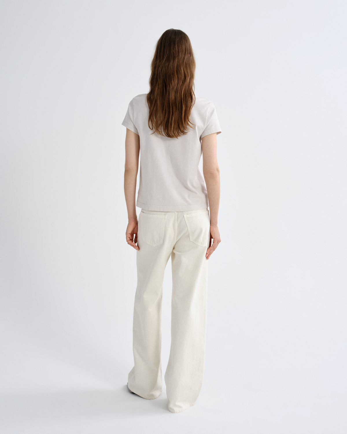 Person wearing a white t-shirt and pants on a light gray background