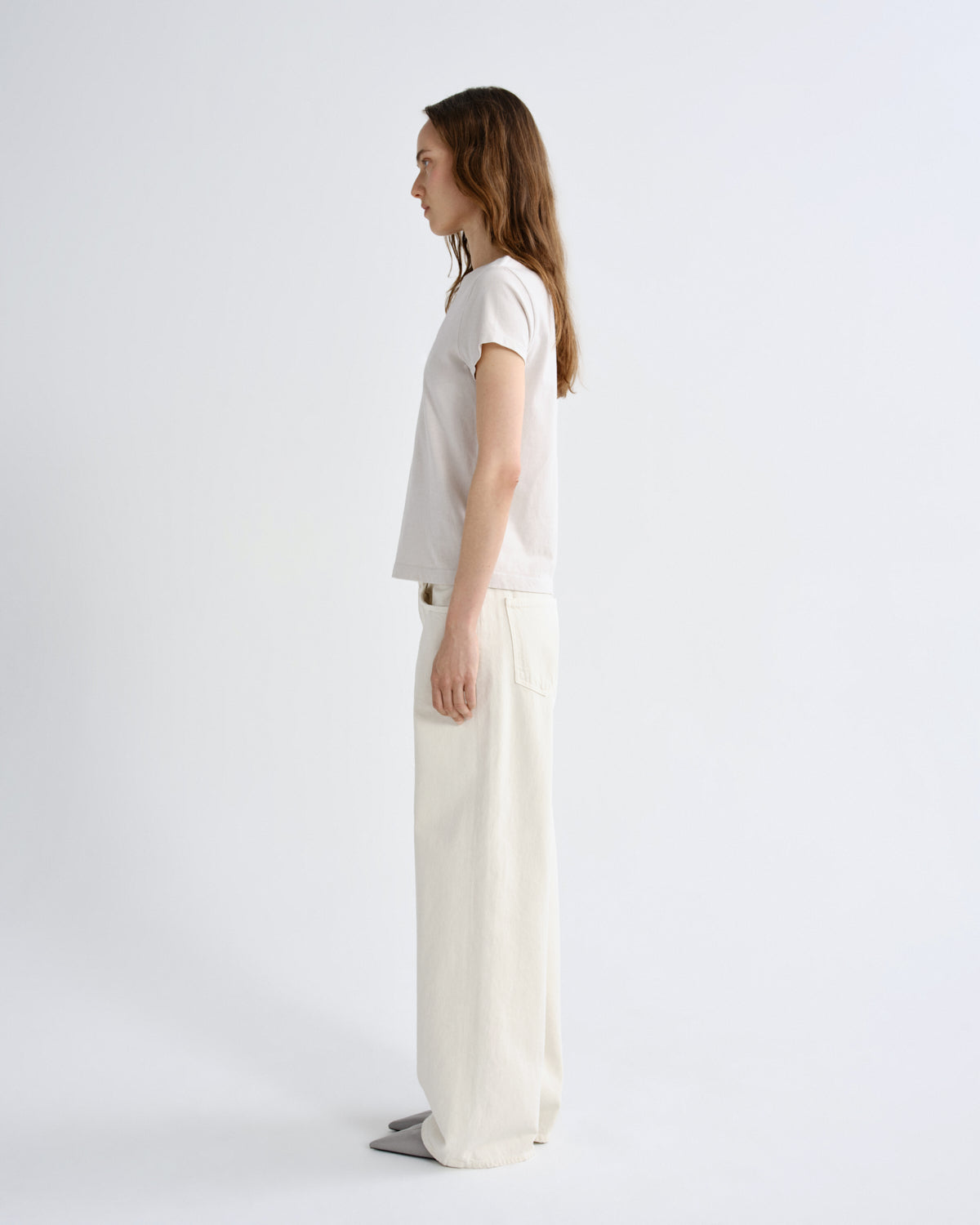 Woman wearing a white t-shirt and cream pants on a white background