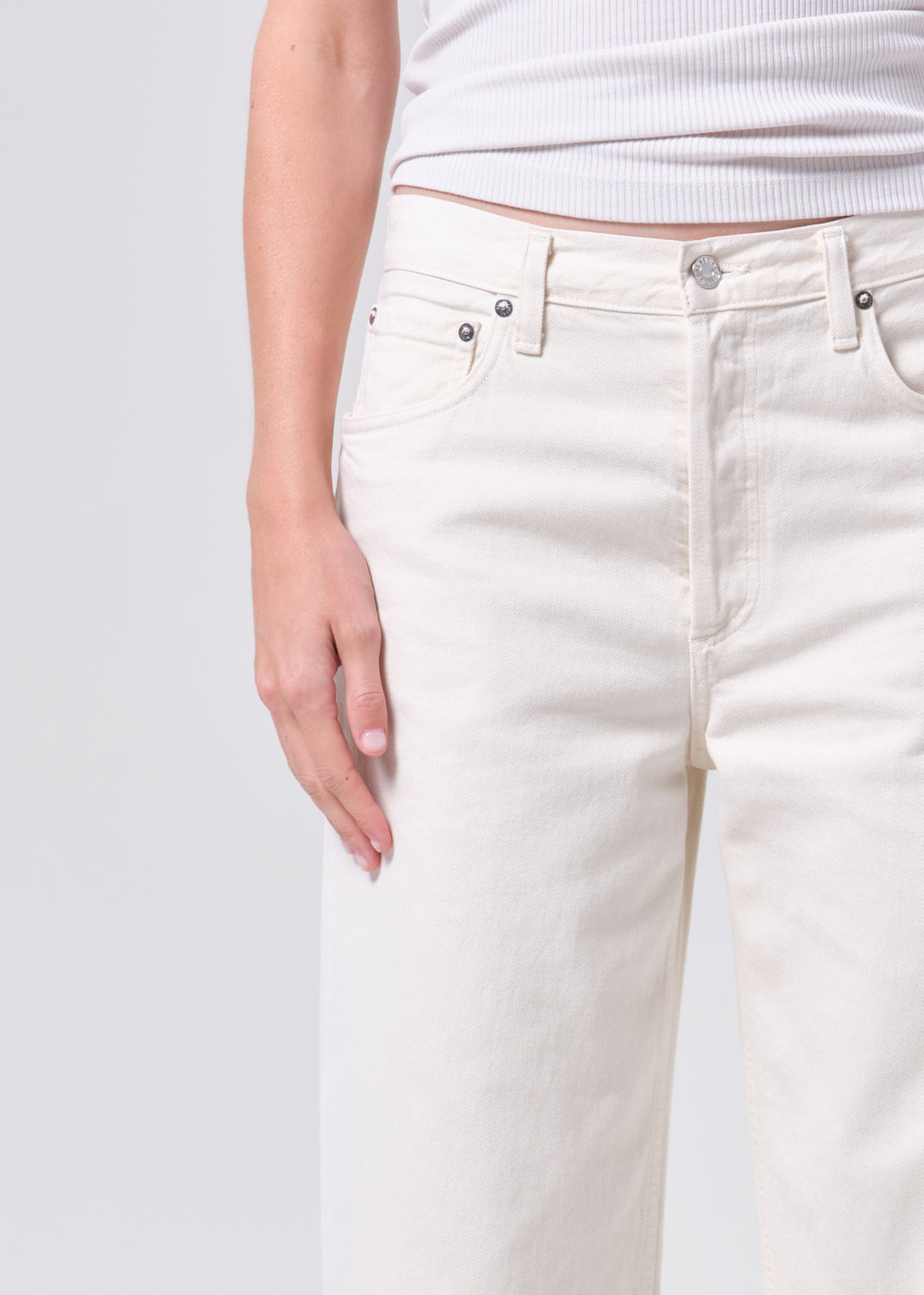 White jeans worn by a person on a light gray background