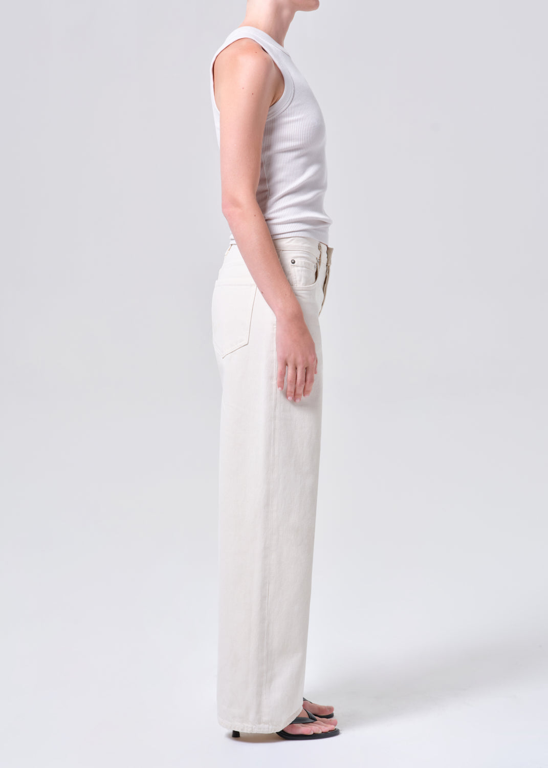 Person wearing a white sleeveless top and wide-leg pants on a plain background