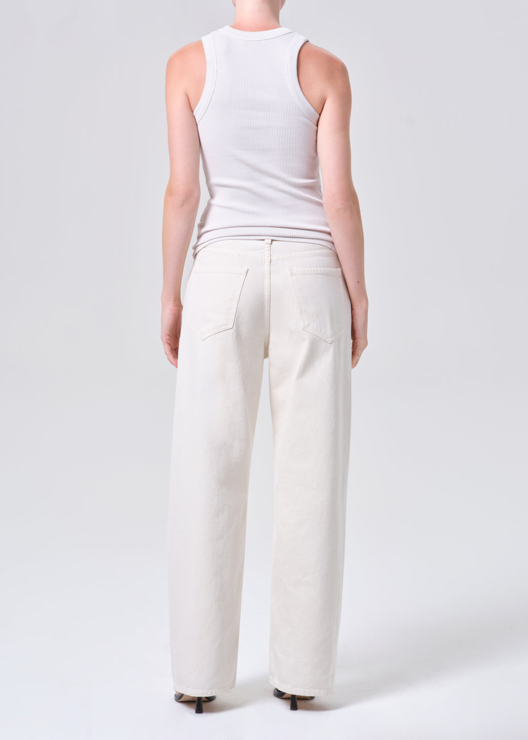 Person wearing a white sleeveless top and wide-leg pants on a light gray background